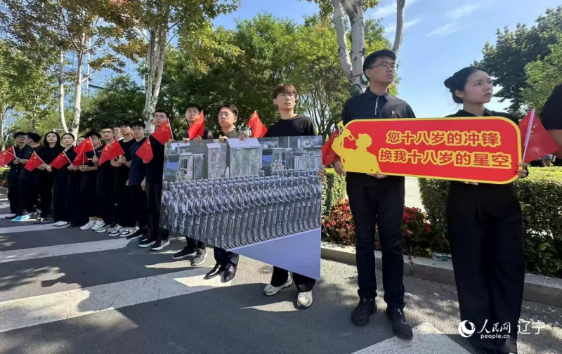 沈陽市人民廣場上,大學(xué)生們手持閱兵的圖片,告慰英烈。人民網(wǎng)記者 周頌雪攝